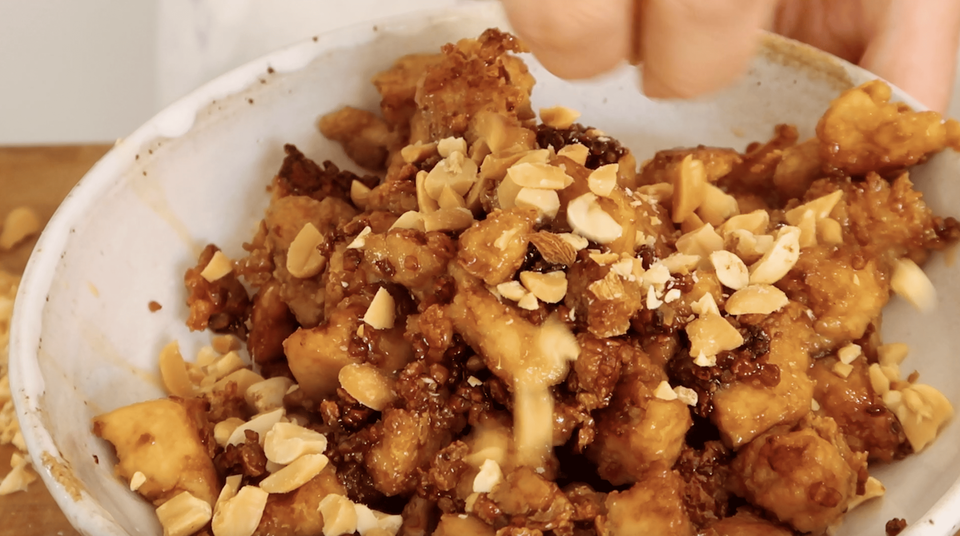 sweet soy tofu being topped with peanuts