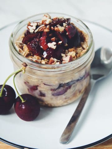 diners view of a jar of overnight oats layered with cherries