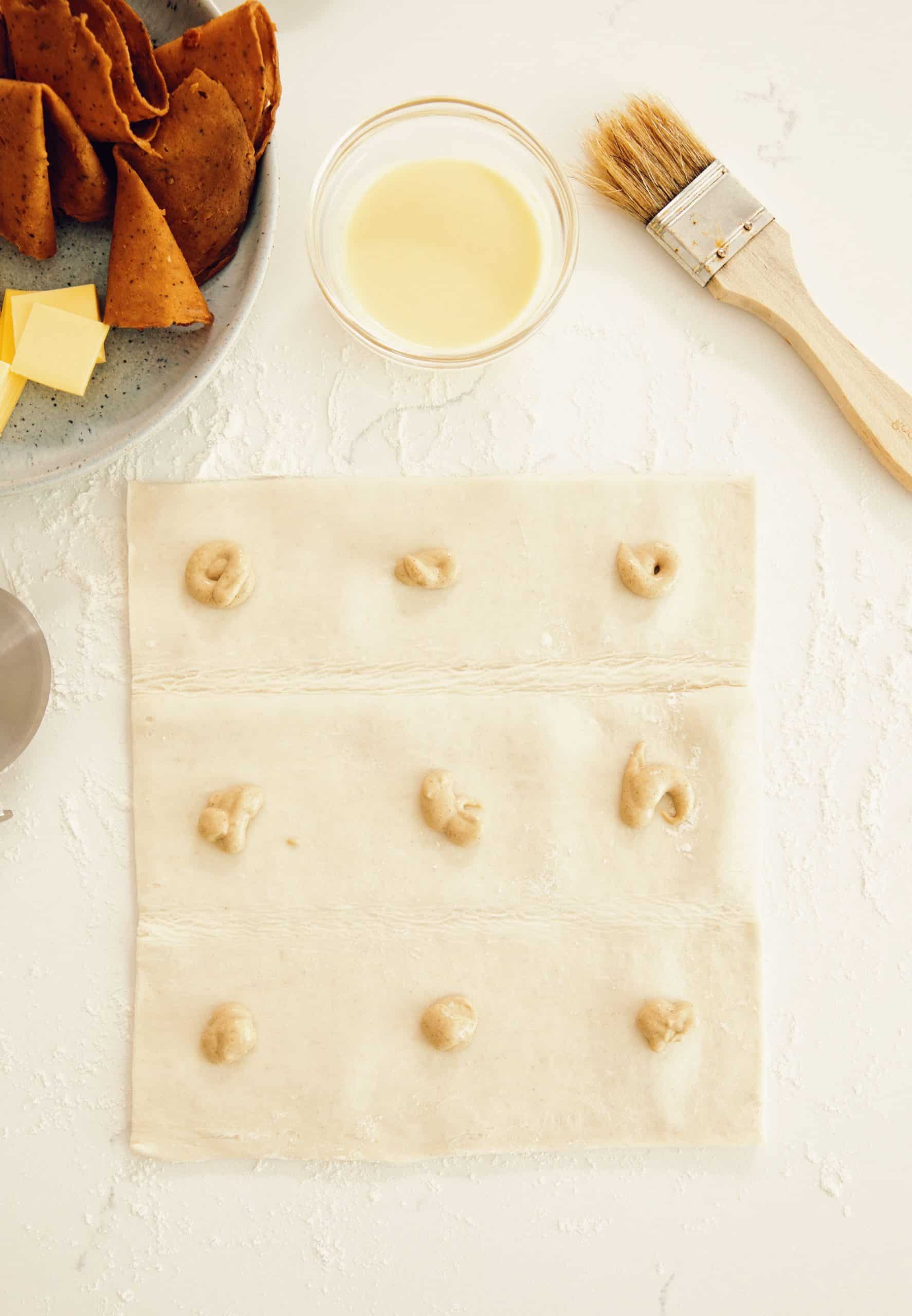 overhead of a puff pastry sheet scored into squares with Dijon mustard placed on each square